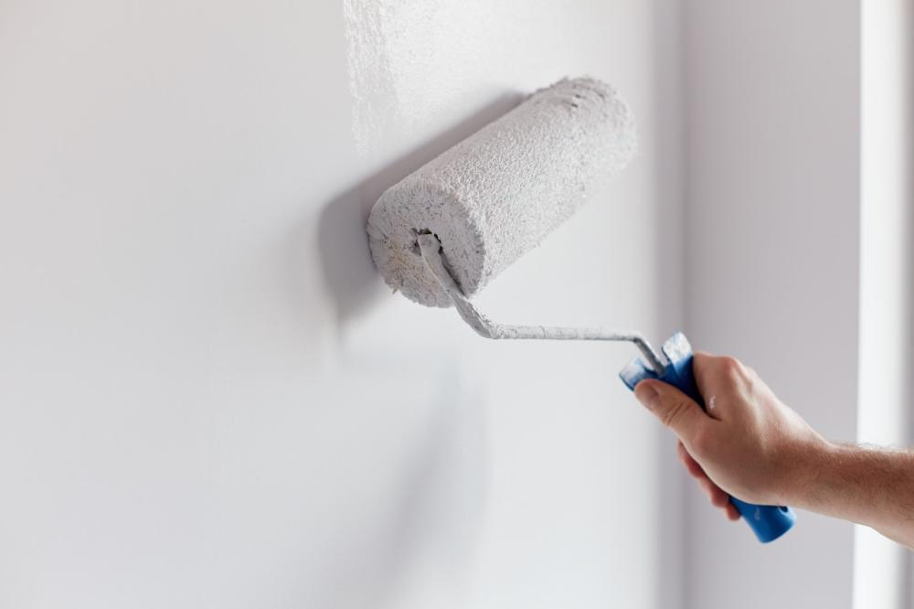 Un peintre passant une couche au rouleau en intérieur